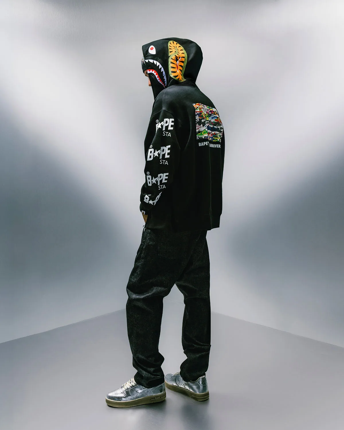 Side view, person in black shark hoodie with silver sneakers on feet, Future