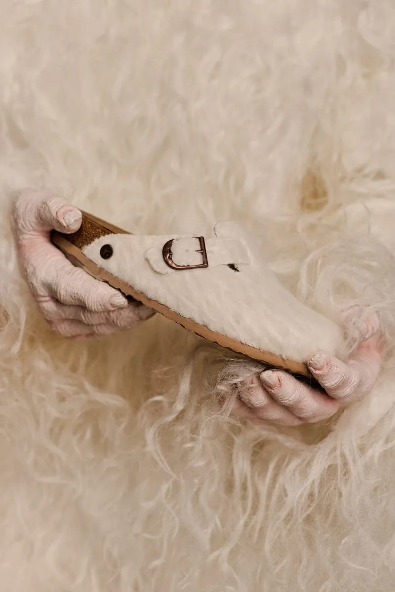 in-hand, single clog held against matching wooly white fur backdrop, Wooly Moon Buckle