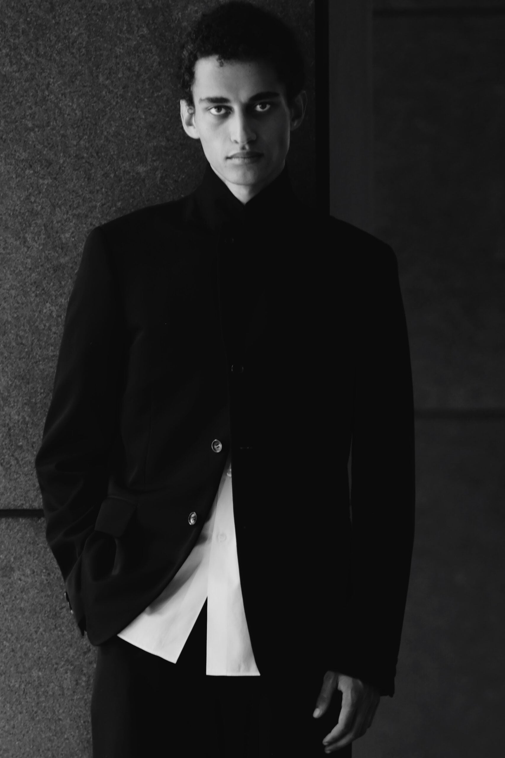 Close-up portrait, black tailored jacket over white shirt, dark backdrop, Air Jordan 11
