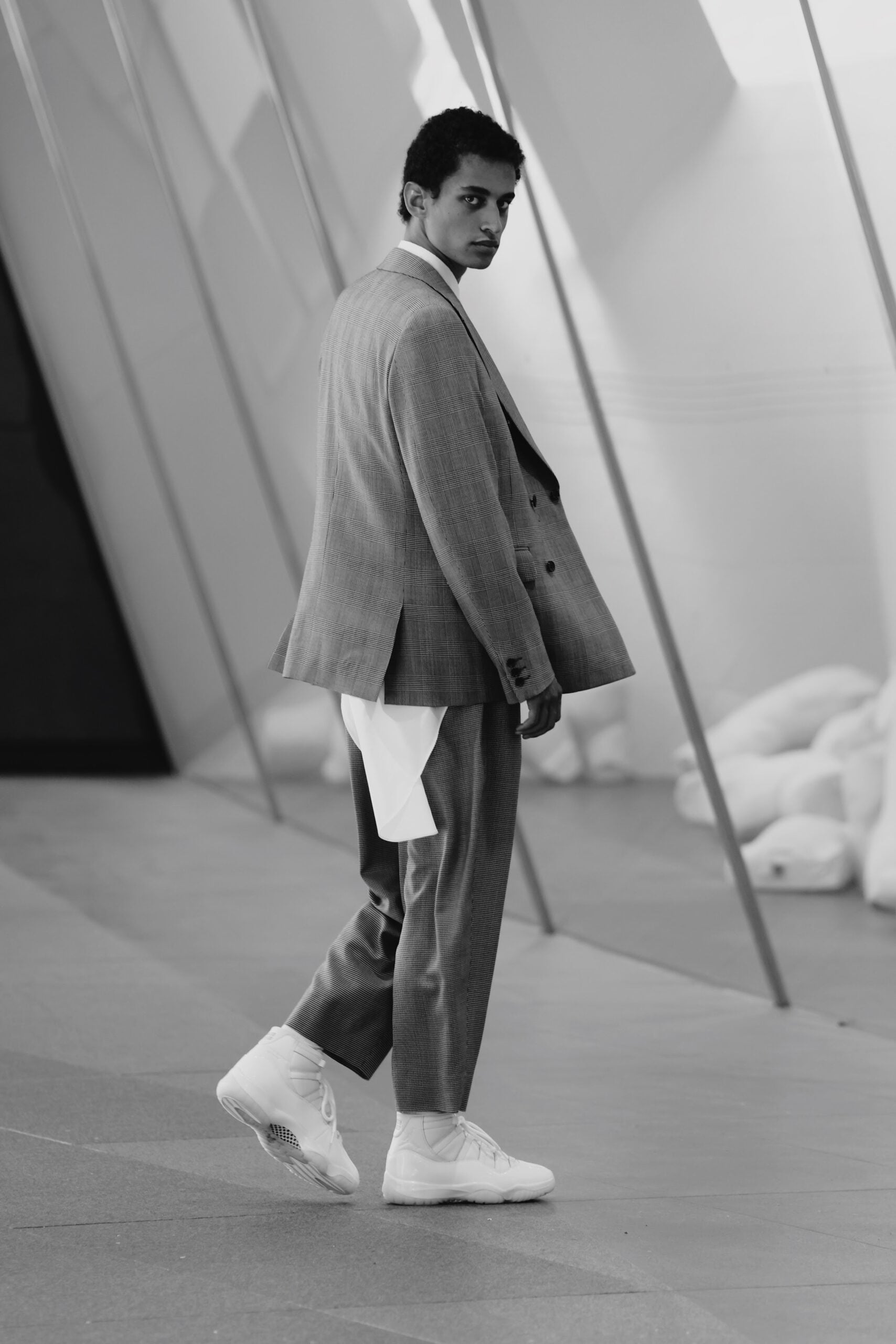 Full-length side view, grey plaid oversized suit with white high-top sneakers, Air Jordan 11