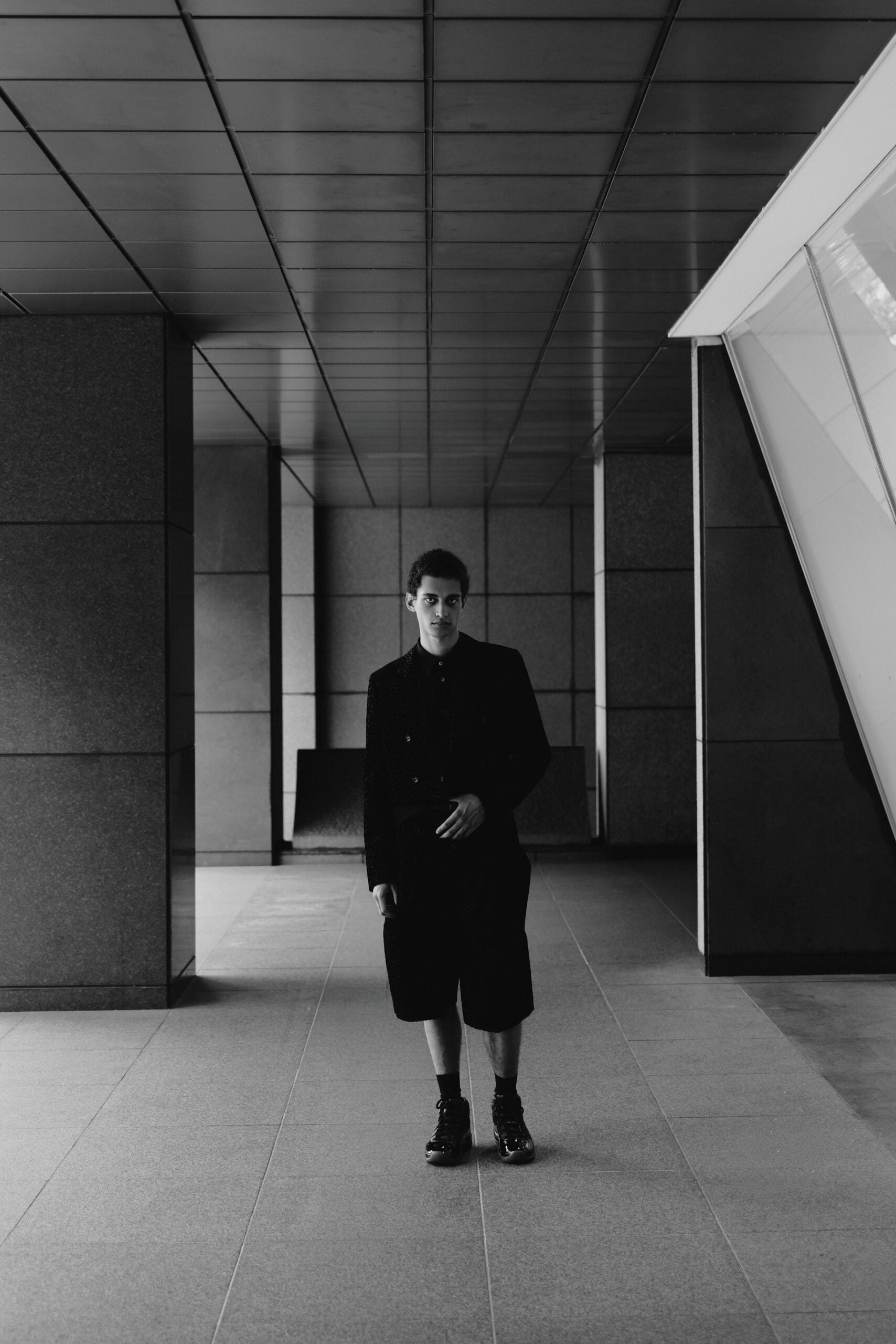 Front view, black textured jacket and shorts with black high-top sneakers, Air Jordan 11
