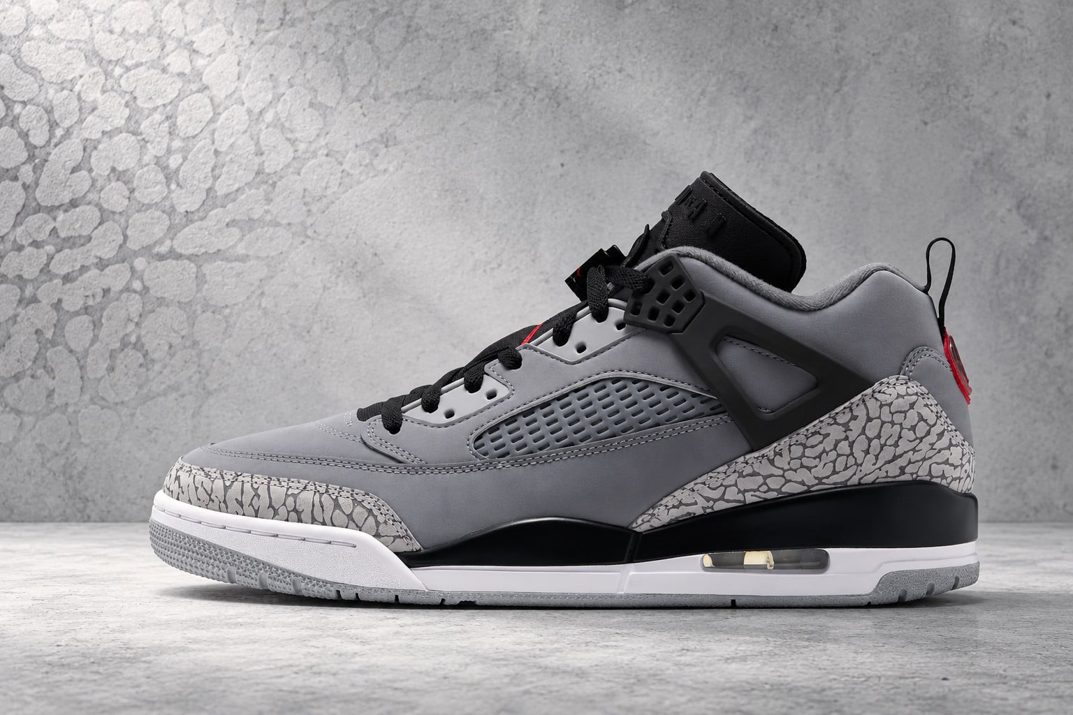 Lateral view against mottled grey backdrop, black tongue, elephant-print toe, Jordan Spiz’ike Low “Cool Grey”
