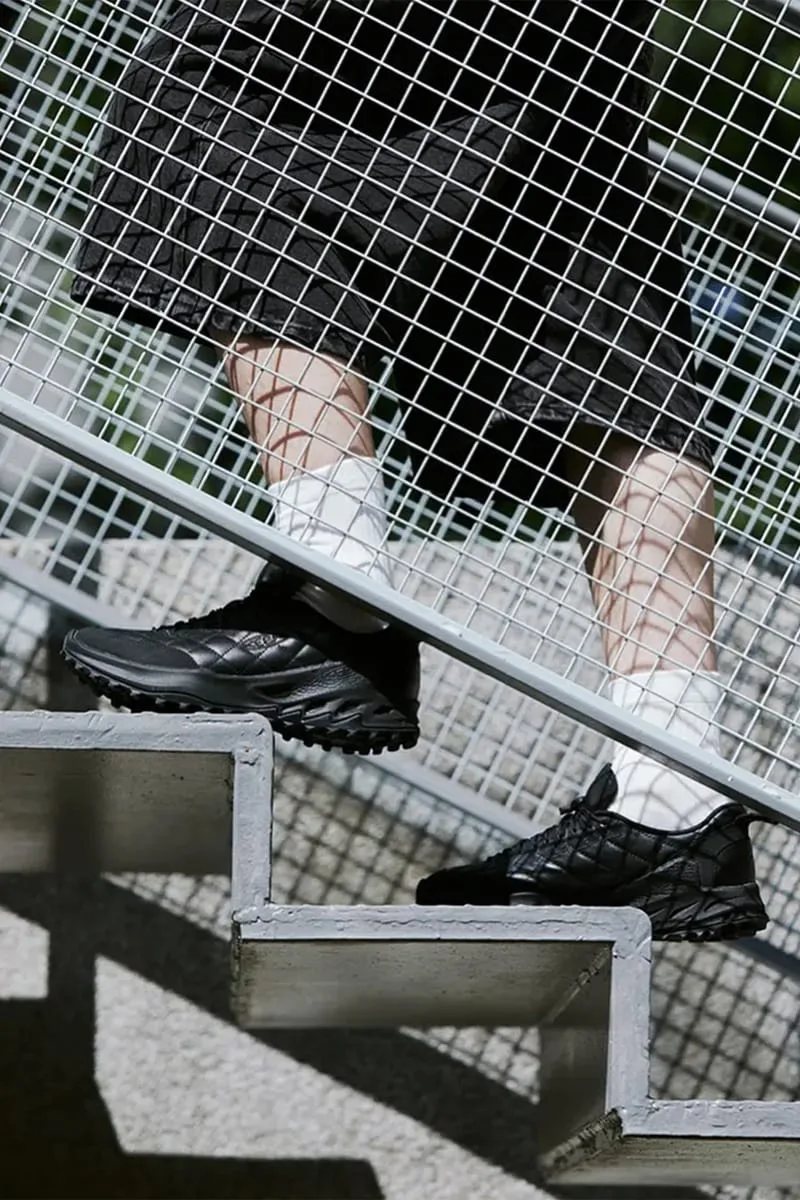 on-foot pair on outdoor stairs, black quilted sneakers with white socks and mesh railing, DOE Jasper Zionic