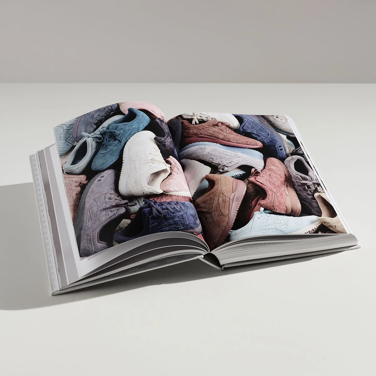 open book tilted, spread filled with pastel suede sneakers piled together, The Footwear Archive