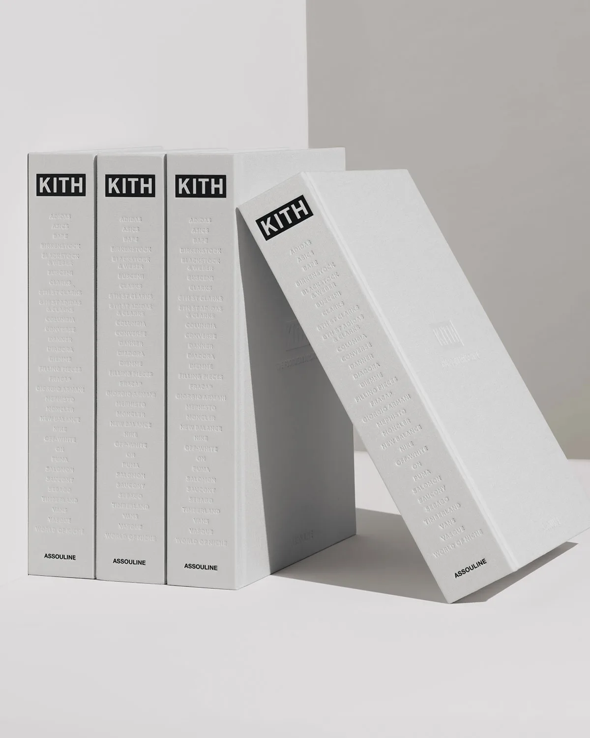 four grey hardcover books leaning together, spines embossed kith, The Footwear Archive