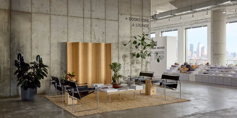 Kith lounge with concrete walls, low chairs, plants and a bookshop sign beside a light wood partition