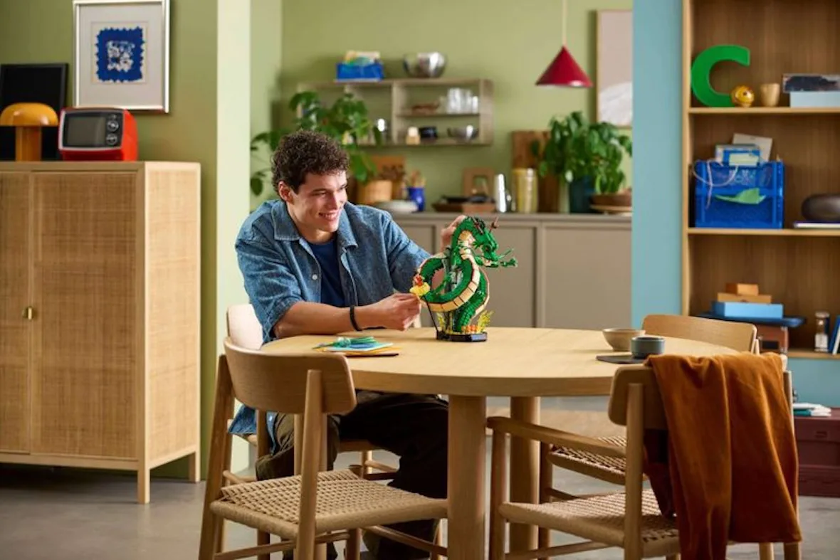 lifestyle shot of man building dragon set at round wooden dining table, Shenron & Goku