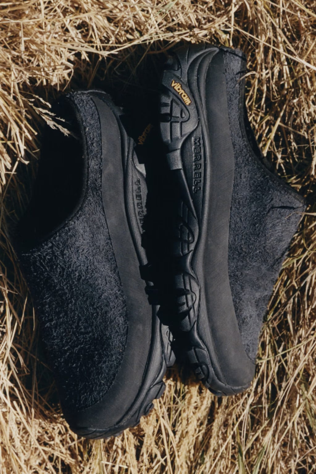 Pair on dried hay, black shaggy suede slides with black Vibram soles, Slide x YMC