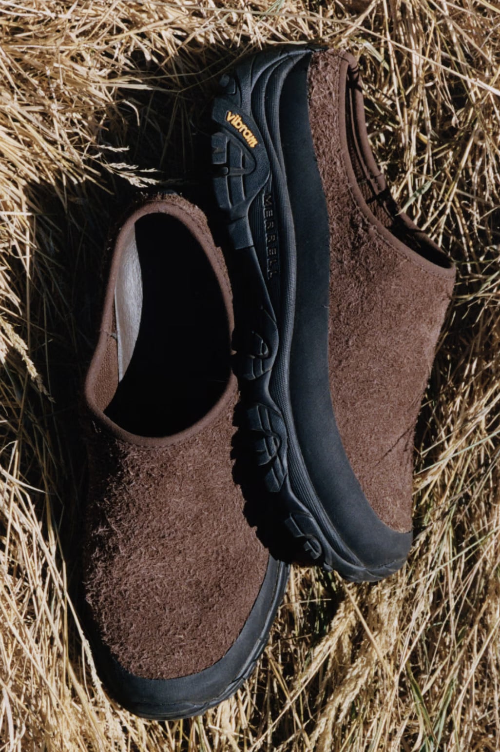 Pair on dried hay, brown shaggy suede slides with black Vibram soles, Slide x YMC