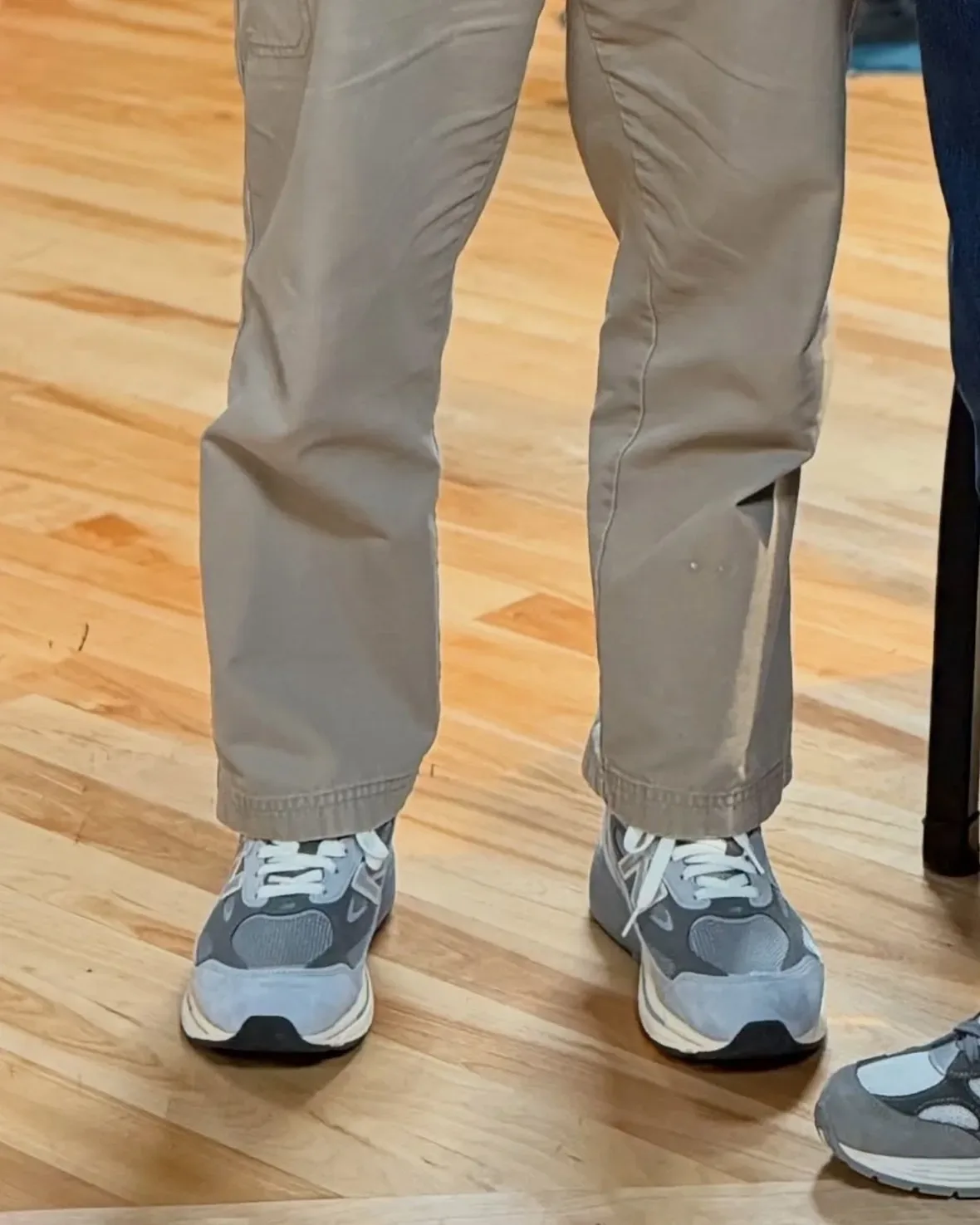 on-foot close-up, grey suede sneakers with white laces and khaki pants, New Balance 990v7
