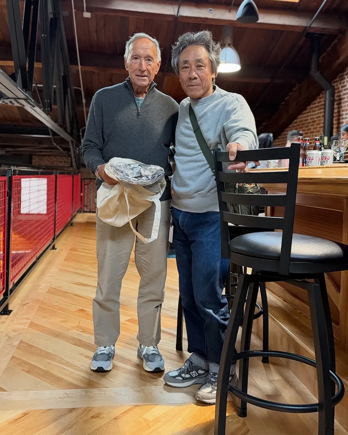 on-foot pair, two men in grey New Balance sneakers on wood floor indoors, New Balance 990v7
