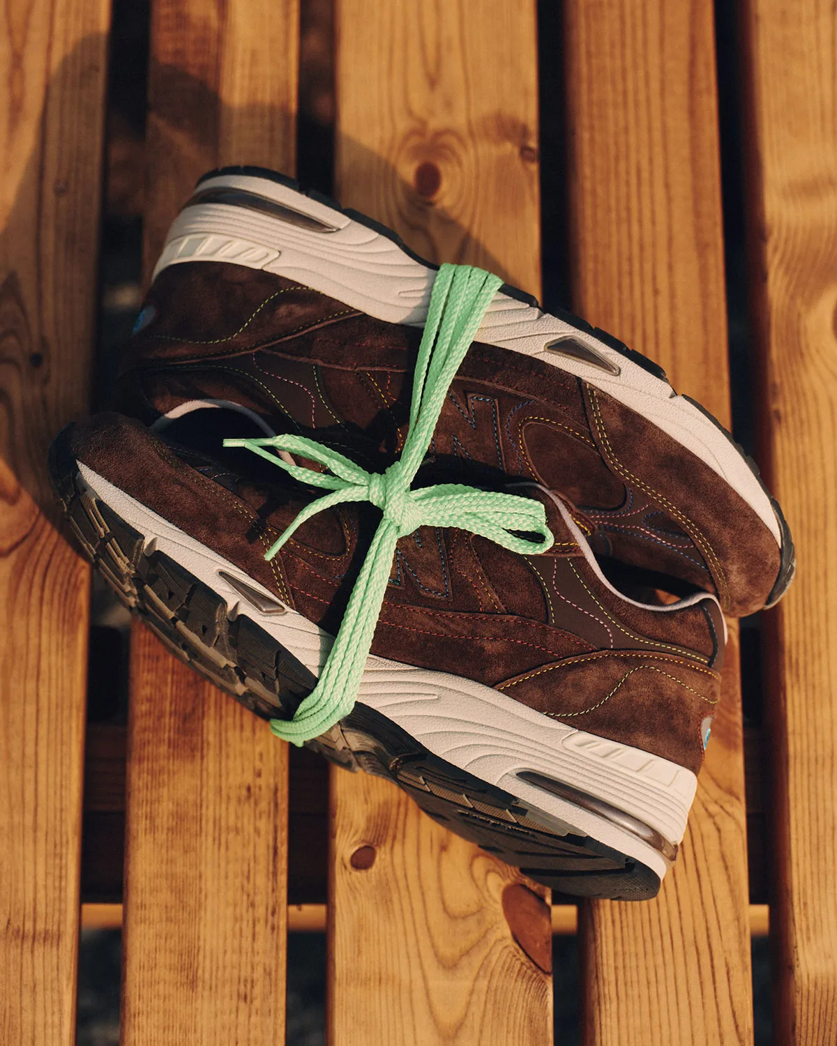 pair laced together, brown suede with mint green laces on wood decking, New Balance 991v1 x Bleue Burnham in Brown/Blue