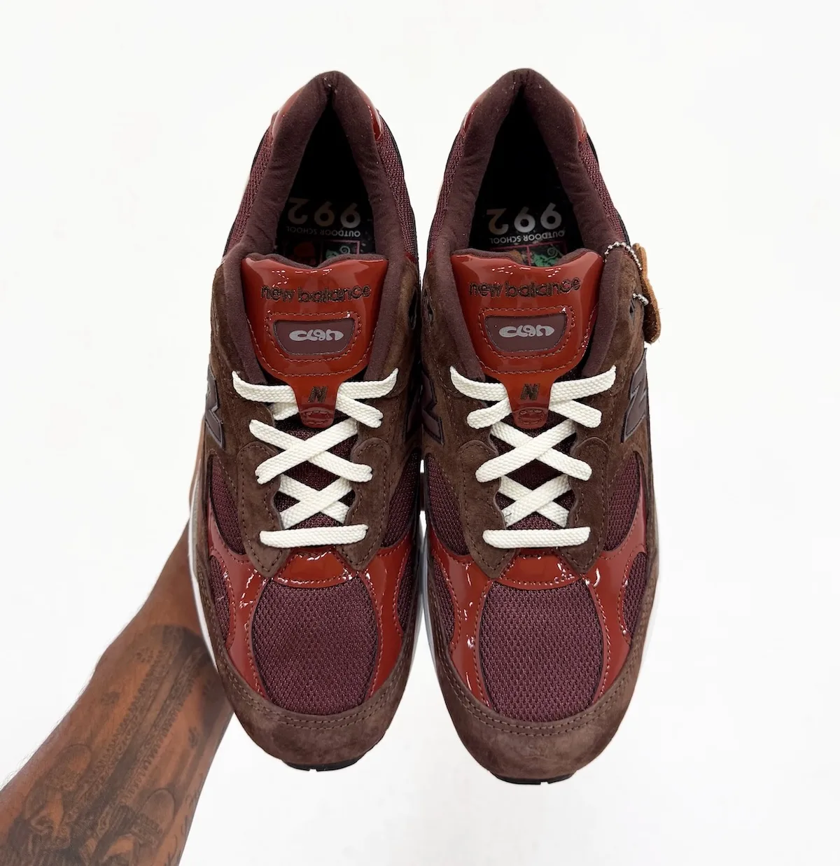 top-down pair view, brown suede toes with red patent overlays and white laces, Outdoor School