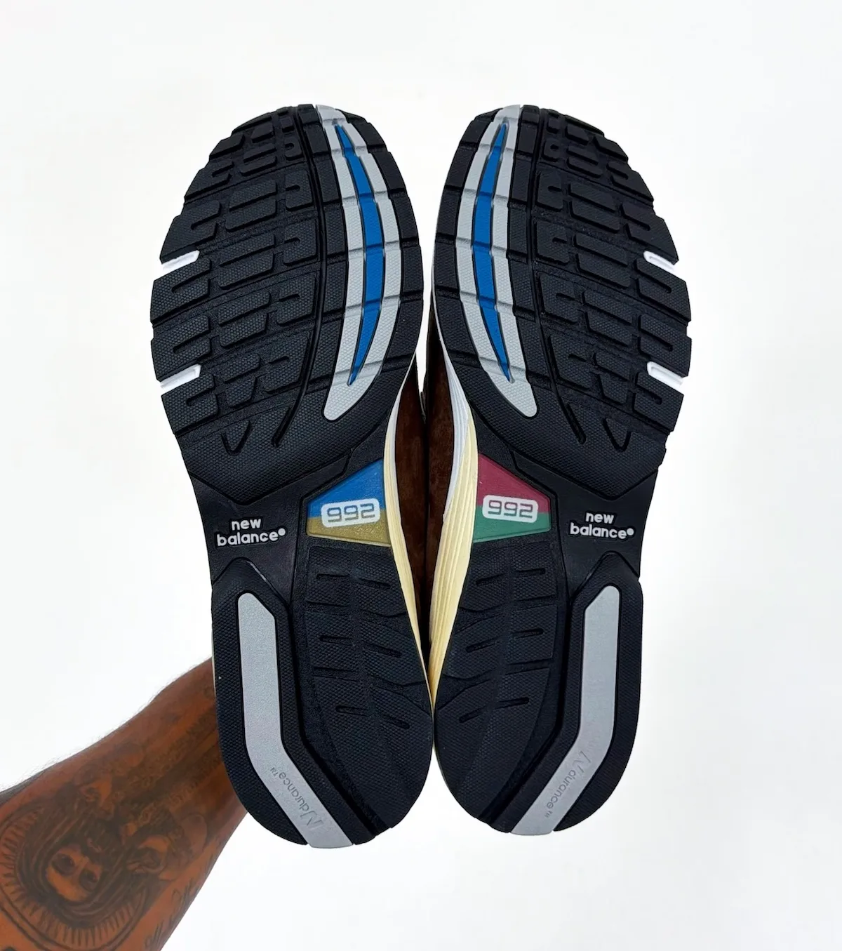 outsole pair view, black tread with blue and grey accents and 992 sole tags, Outdoor School