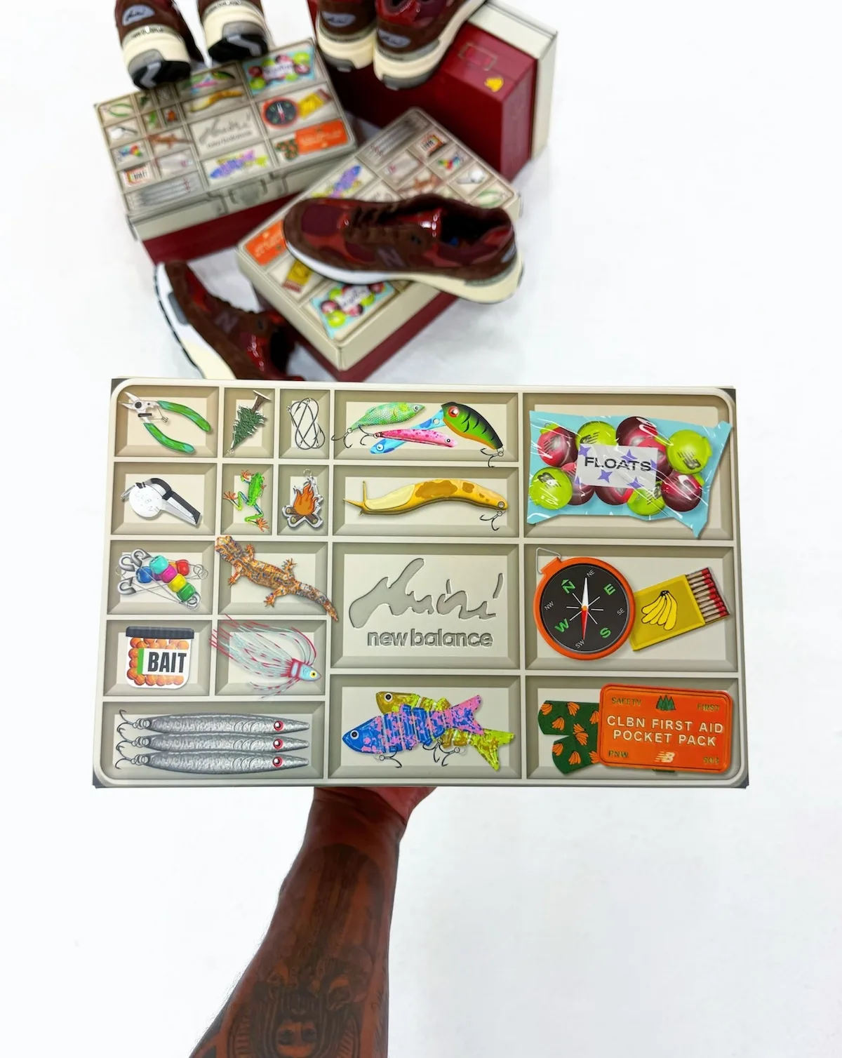 in-hand tackle-box lid graphic showing lures, compass, matches and first-aid icons, Outdoor School