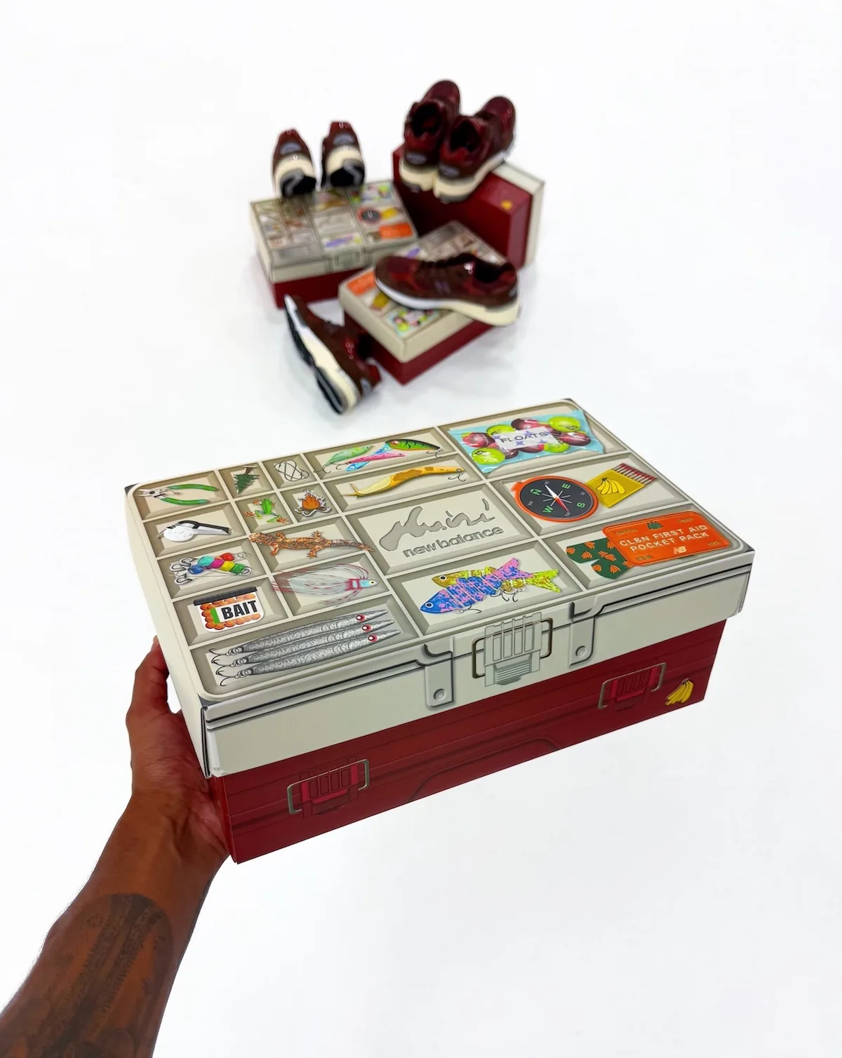 in-hand tackle-box packaging with fishing and outdoor icon graphics, shoes behind, Outdoor School