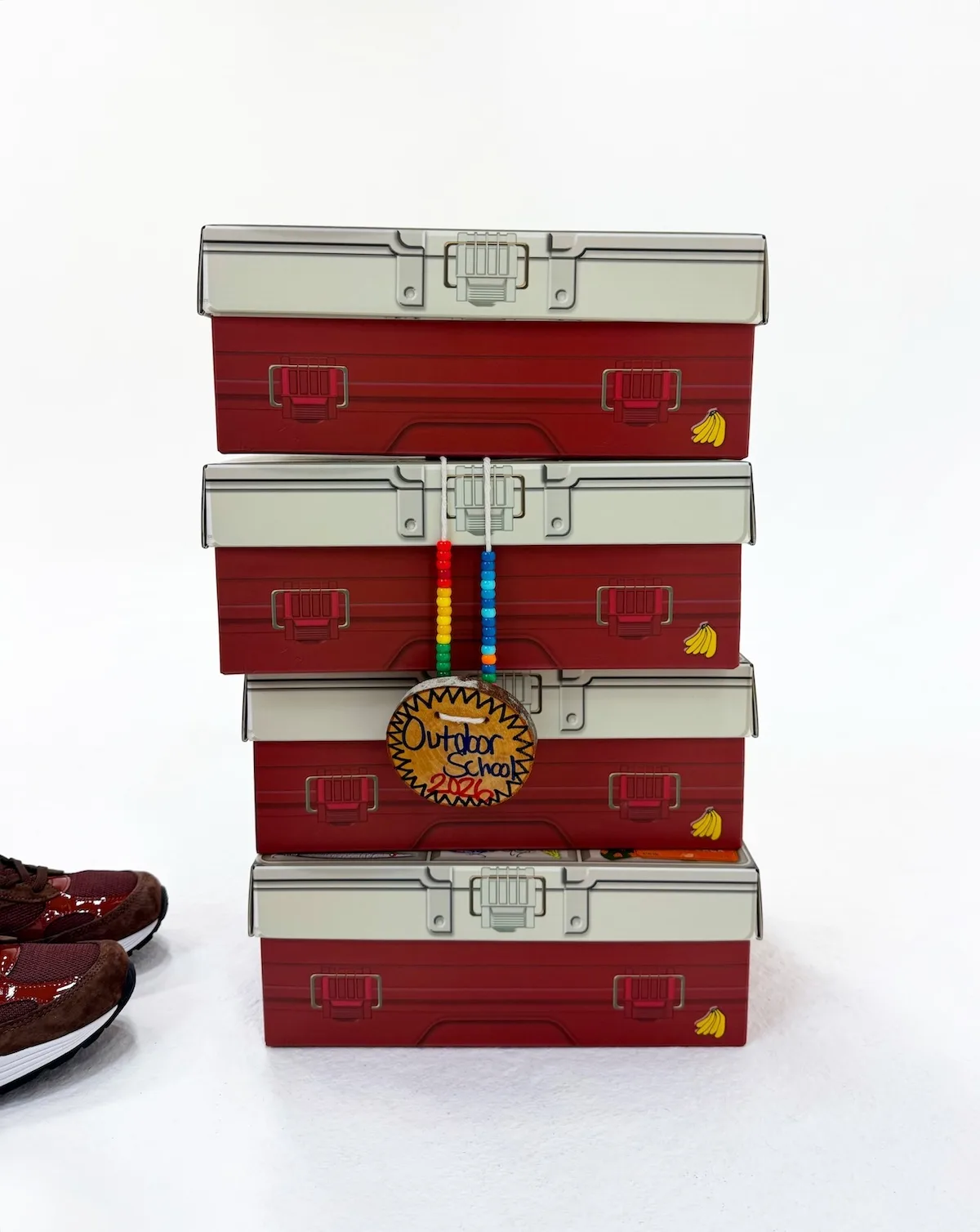 stack of four red tackle-box boxes with a beaded charm hanging off them, Outdoor School