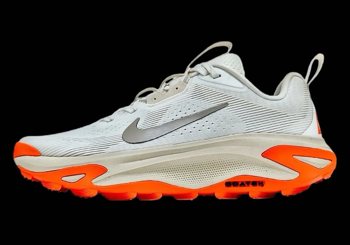 lateral view on black background, white upper with orange outsole and grey swoosh, Nike ACG Juniper