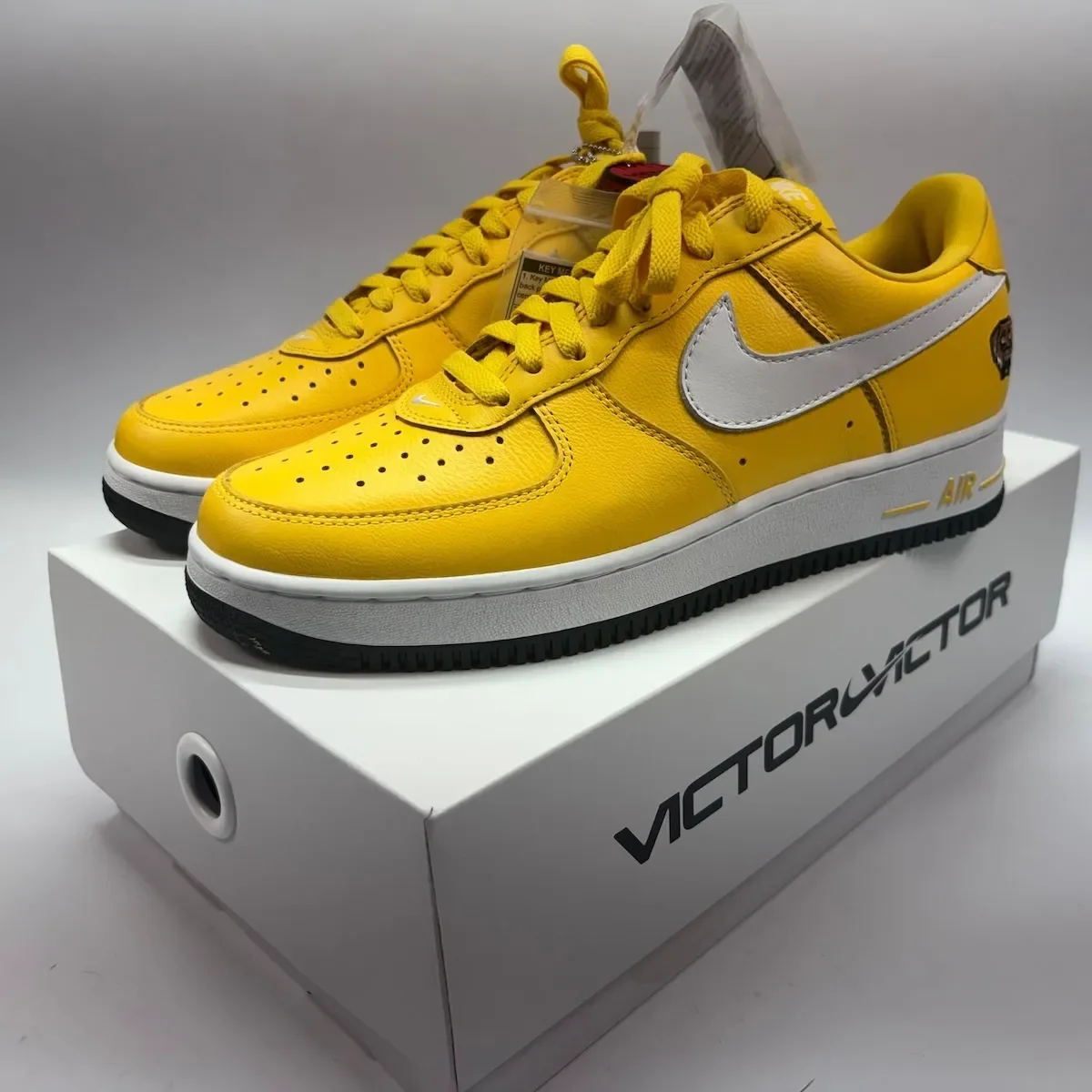 lateral pair in yellow leather with white swoosh, resting on Victor Victor box, Victor Victor Collection