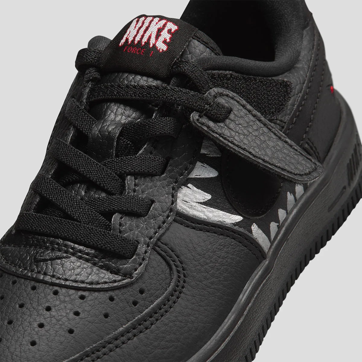 toe and lace close-up, red Nike Force 1 tongue tab and white fang graphic, Beast