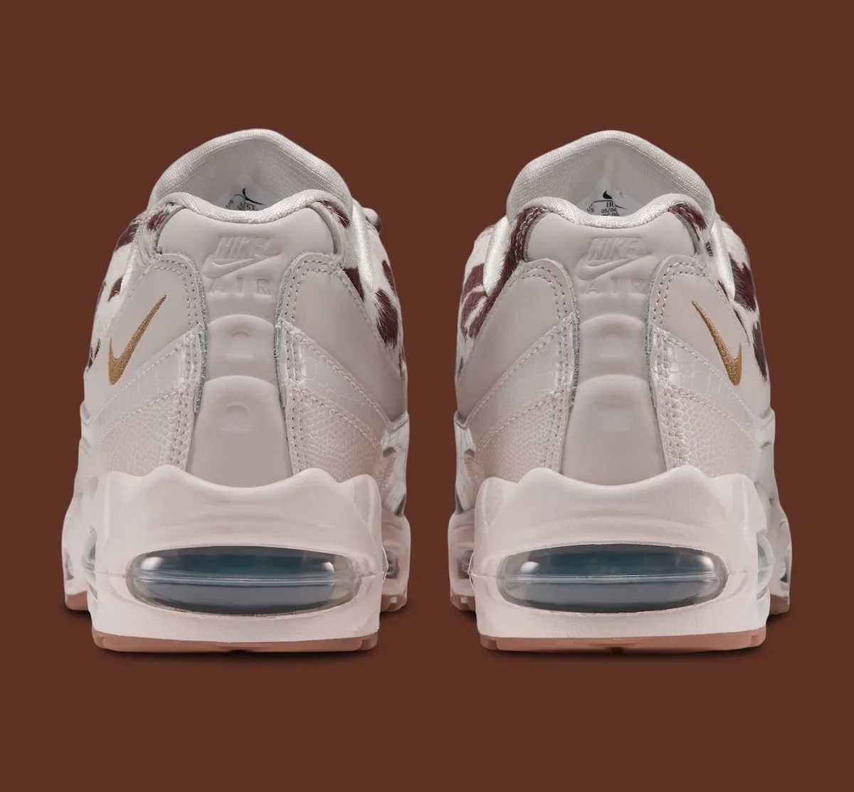 heel view of pair, embossed Nike Air text with gold swooshes on cream heels, Cow Print