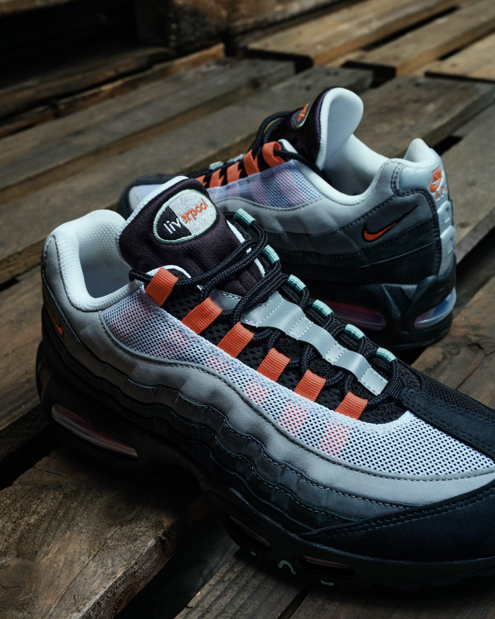 close-up medial pair, white mesh, orange lace loops and grey overlays with 'liverpool' tongue tag, Liverpool