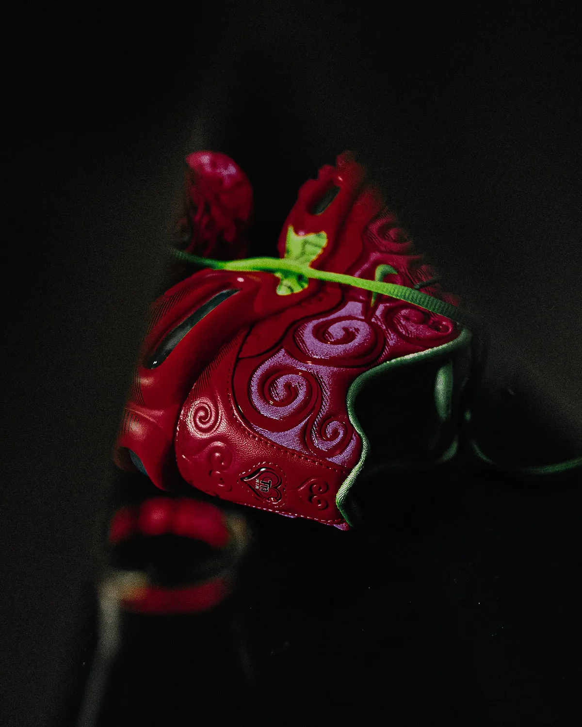 close-up toe detail, red swirl pattern and green pull tab against black background, Ope Ope