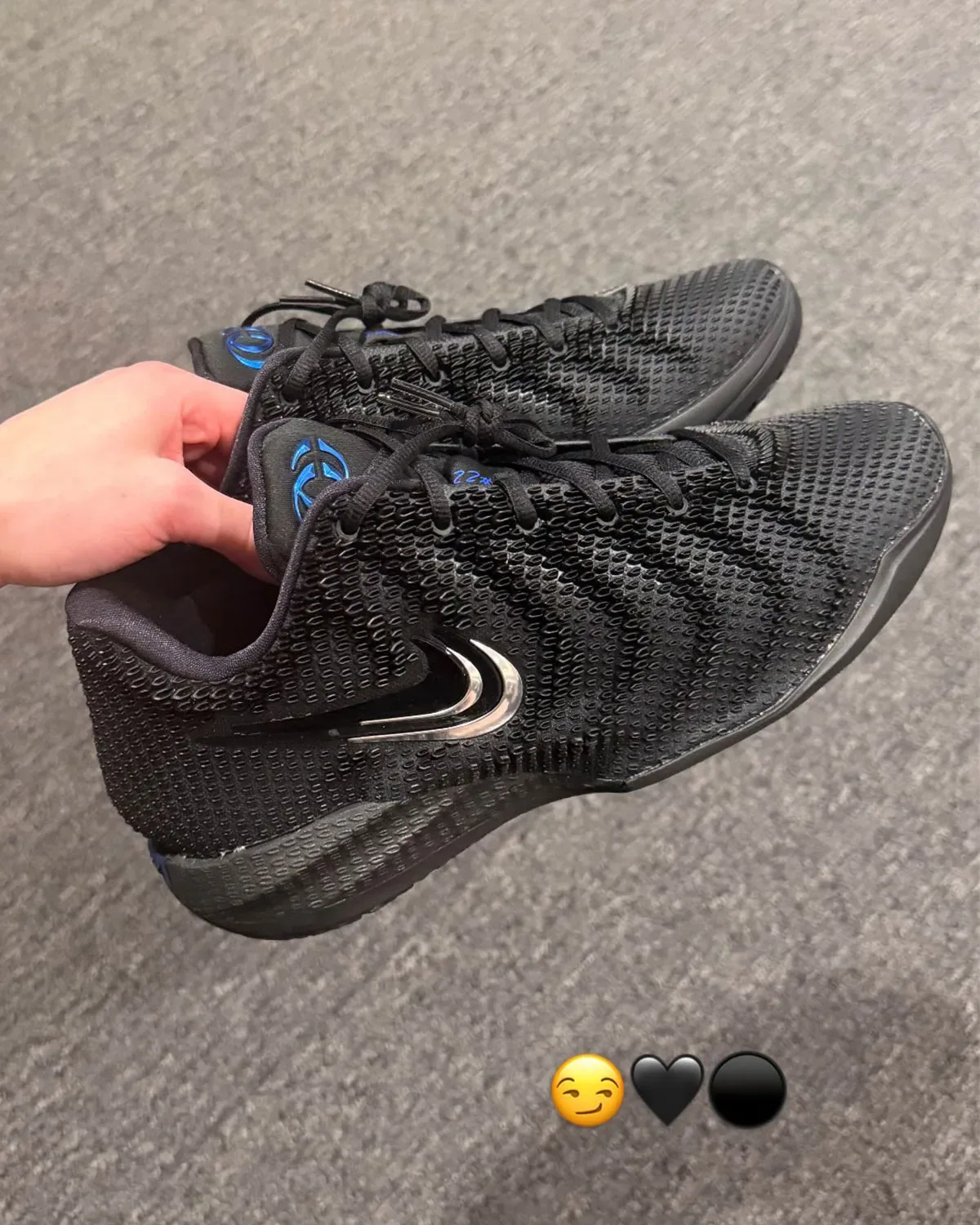 in-hand pair, lateral view, black mesh upper, chrome swoosh, emoji stickers overlaid, 3x Black