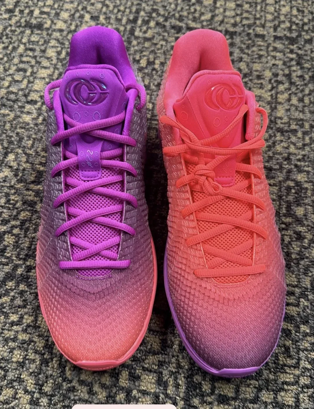 Top-down pair on carpet, purple shoe on left, coral-pink shoe on right, tongue logo, Berry Fade