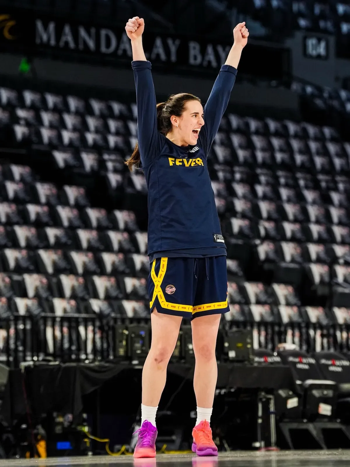 Distant on-foot shot, player celebrating in navy Fever warm-up, shoes at ankles, Berry Fade