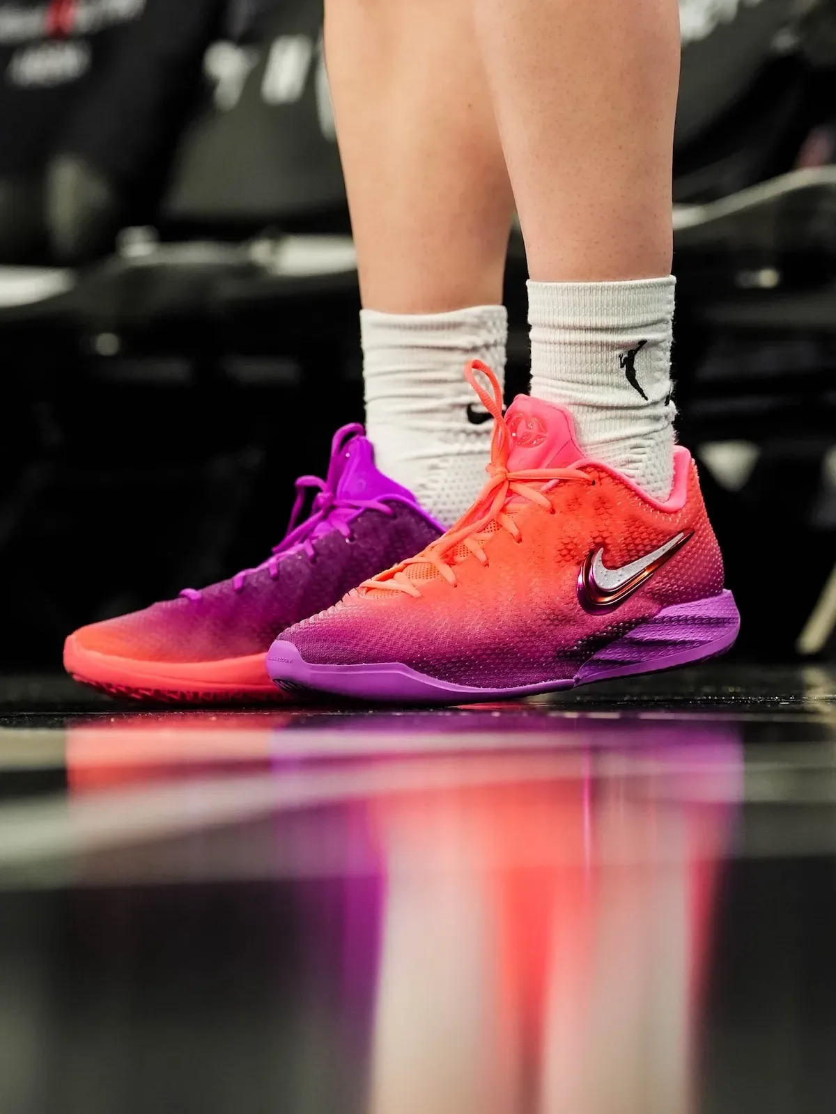 On-foot front view, purple shoe on left foot, orange shoe on right, reflective floor, Berry Fade