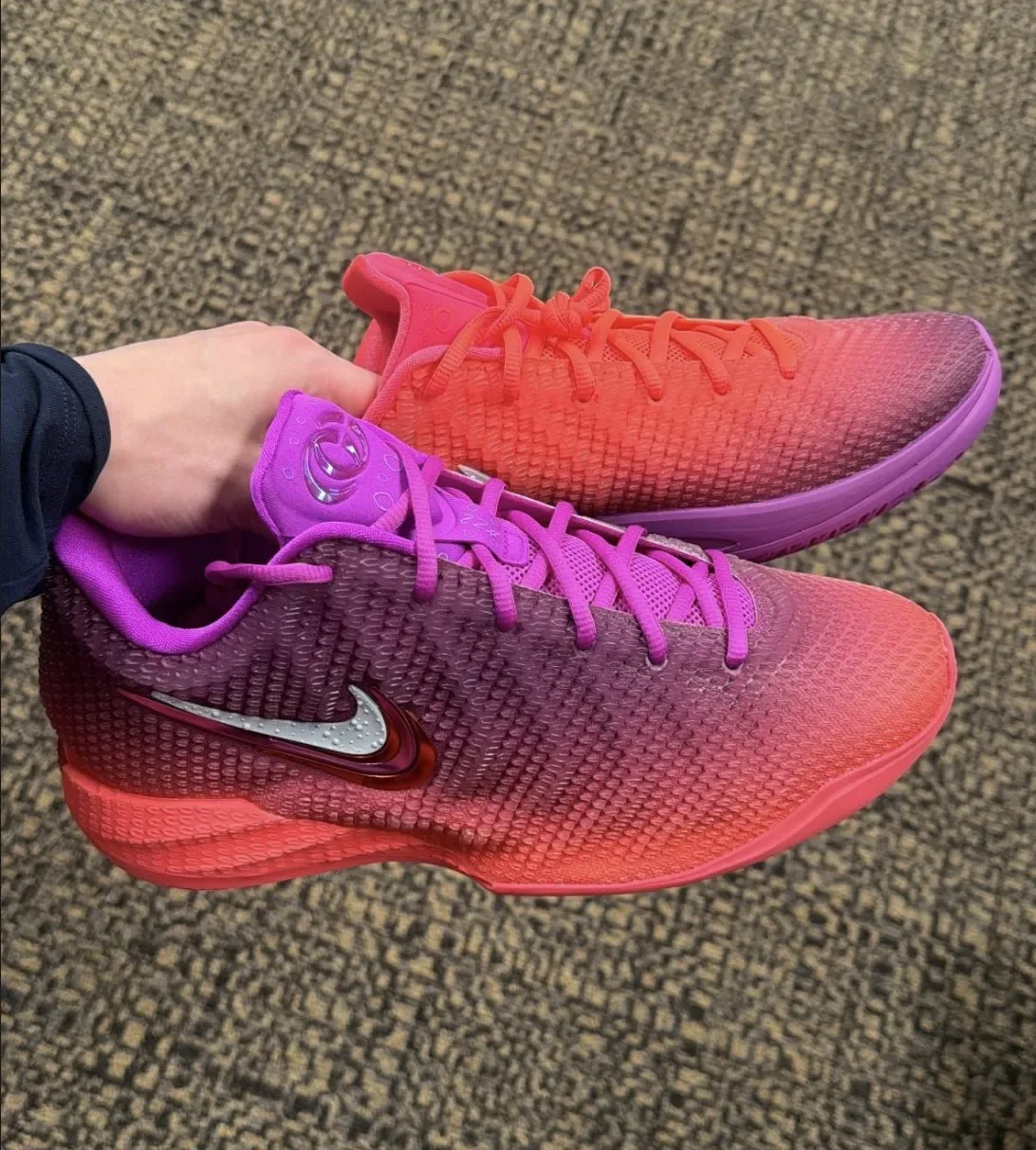 In-hand pair on office carpet, purple-soled shoe crossed over orange one, Berry Fade