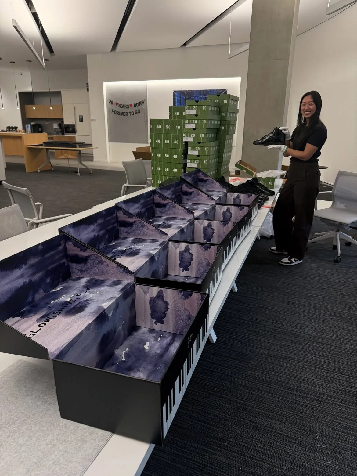 warehouse packing scene, piano-key boxes stacked with green shoeboxes, Maestro 1