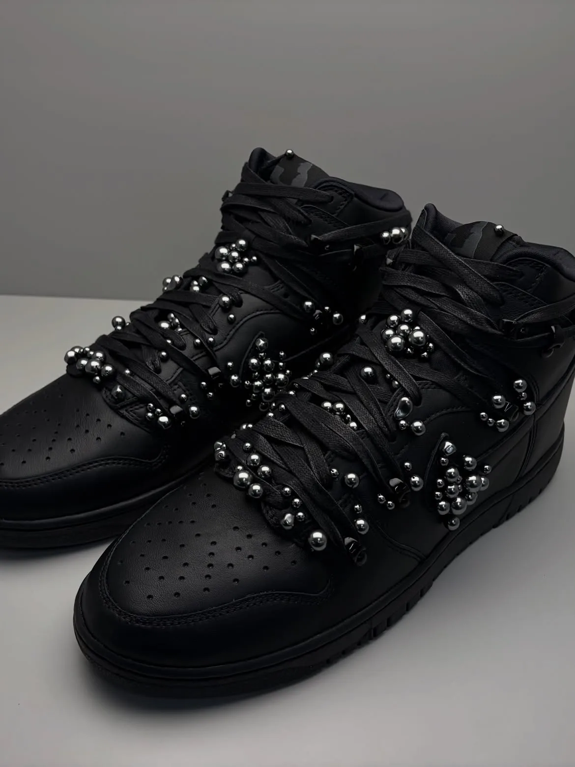 toe-down pair on grey surface, matte black leather with silver bead clusters, Maestro 1