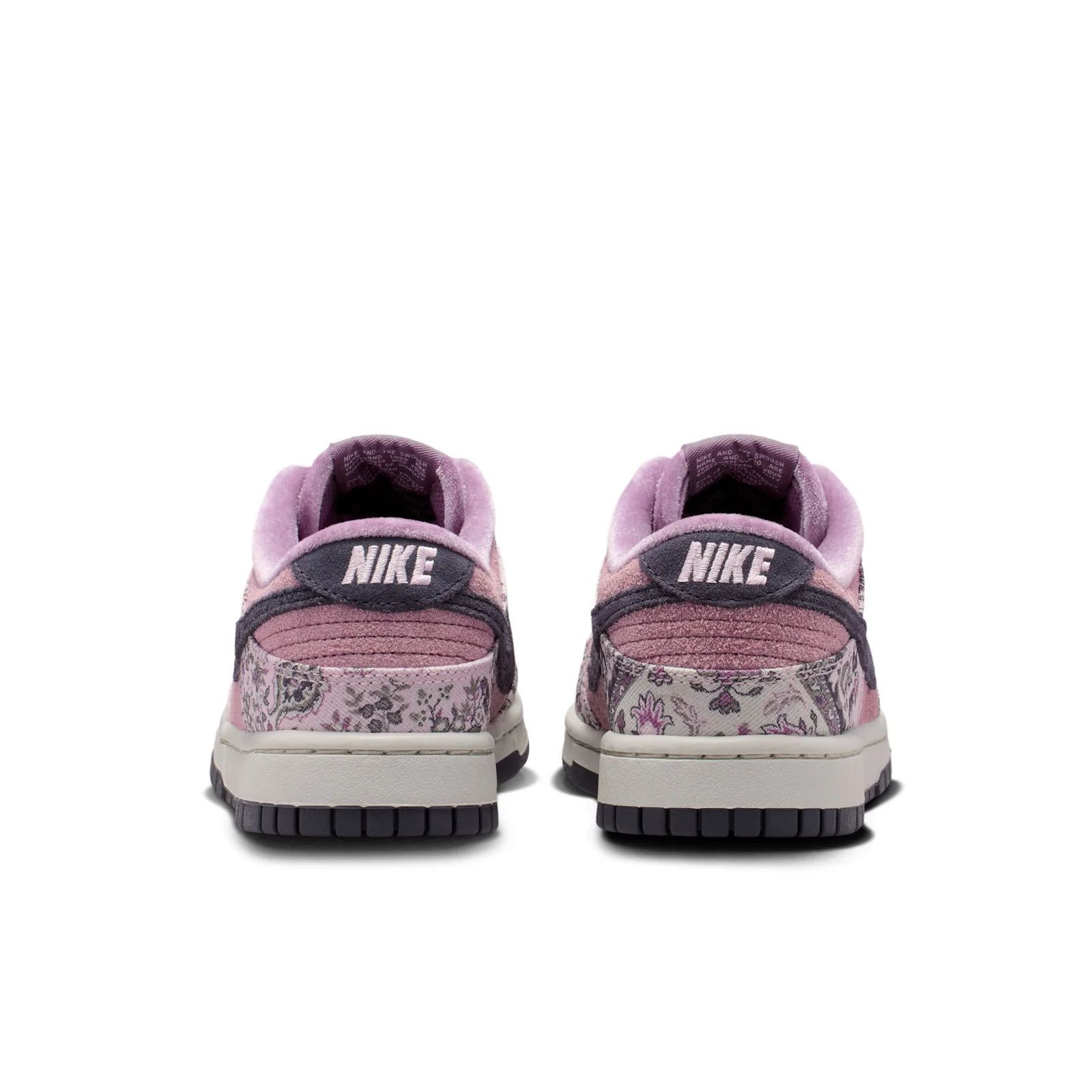 Heel view of pair, dark grey tabs with white Nike text and floral panels, Botanical Rug