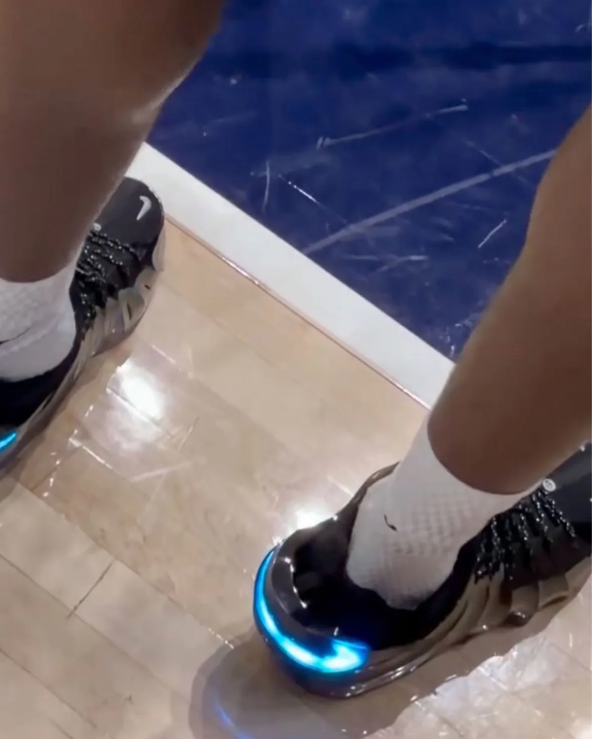 on-foot pair from above, black shoes with glowing blue swoosh accents, Nike GT Flight