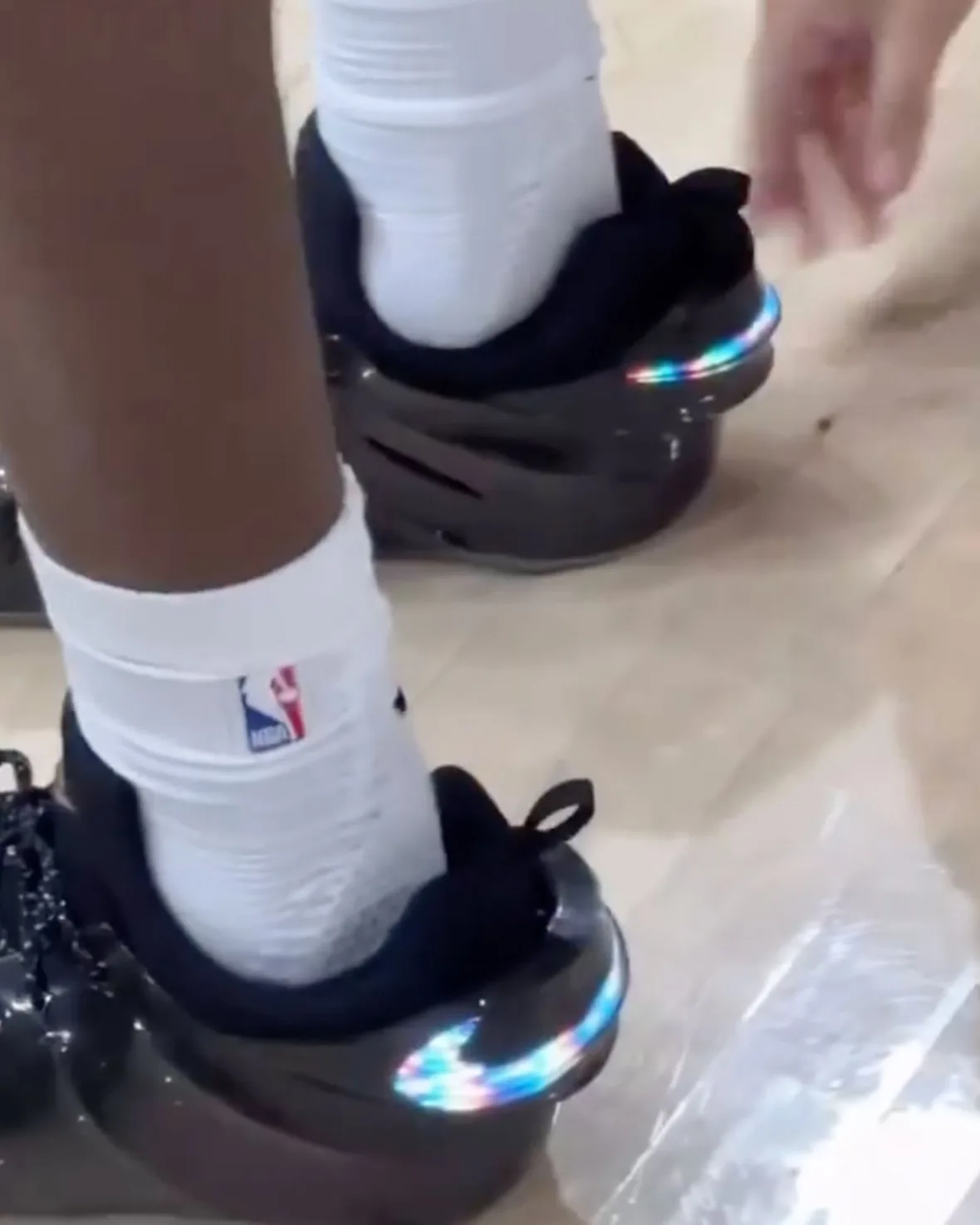 on-foot close-up, black shoe with iridescent swoosh beside a second pair, Nike GT Flight