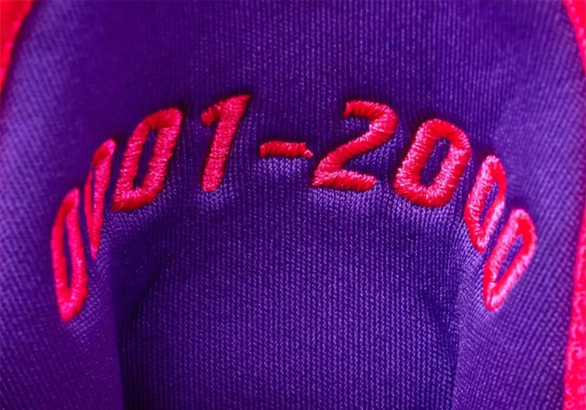 macro detail of purple fabric with red embroidered numeral text, The Better Generation