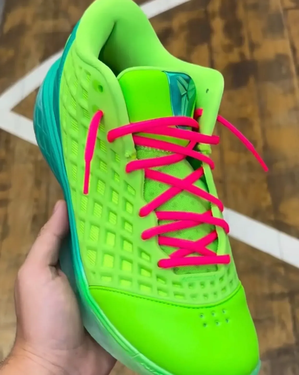 in-hand medial close-up, volt lattice upper, pink crossed laces, teal sole, Grinch