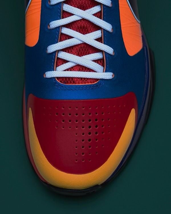 top-down toe close-up, red perforated toe cap with orange trim and white crossed laces, What The Rick