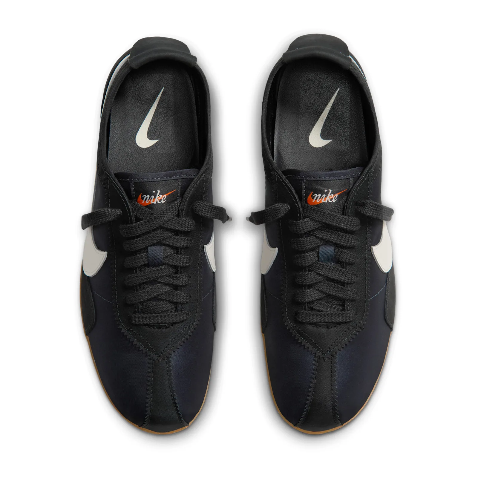 Top-down pair view, black tongues with orange nike script, white insole swoosh, Off Noir