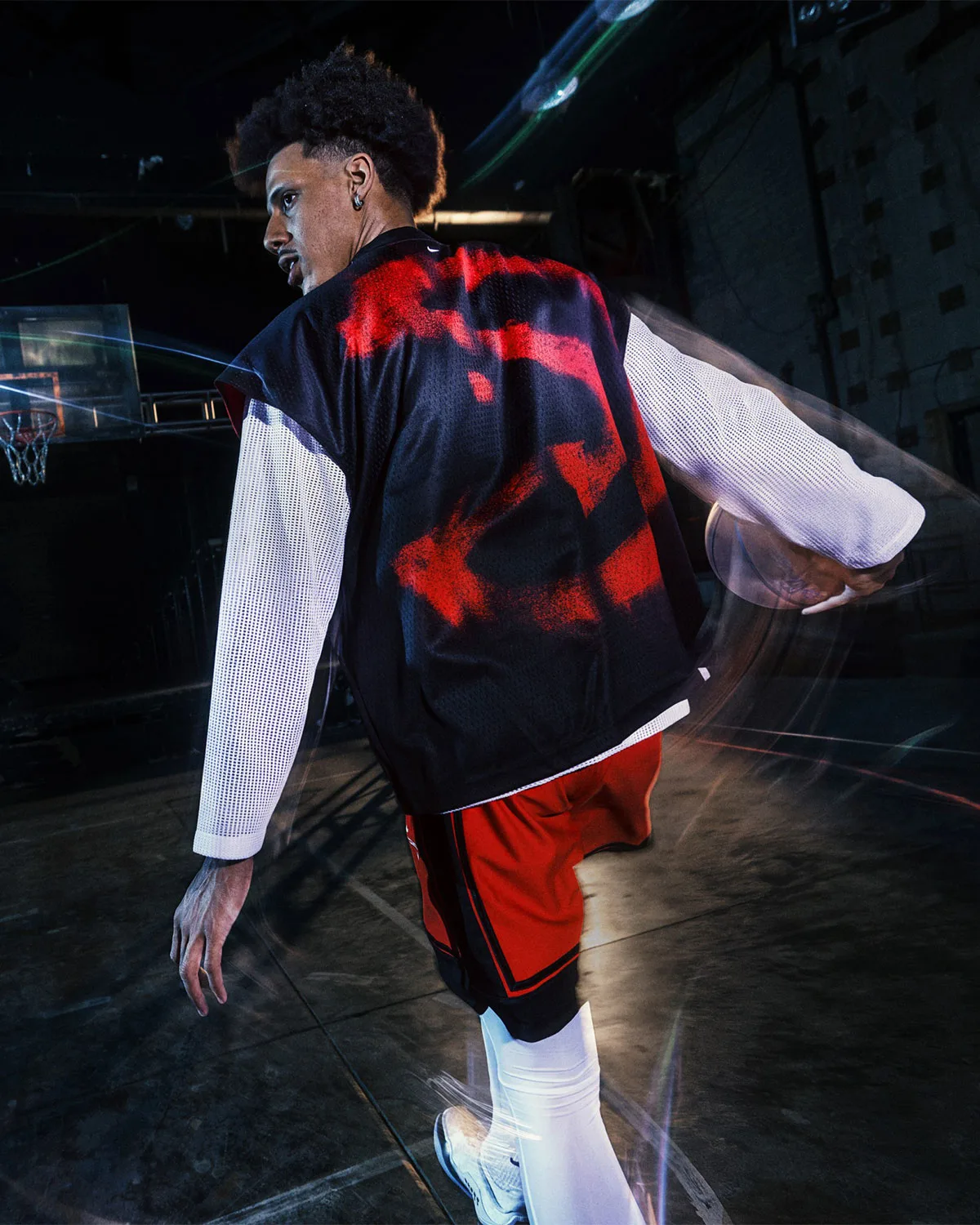 on-court back view, black jersey with red spray-paint graphic, white mesh sleeves, Nike NBA Standard Issue Collection