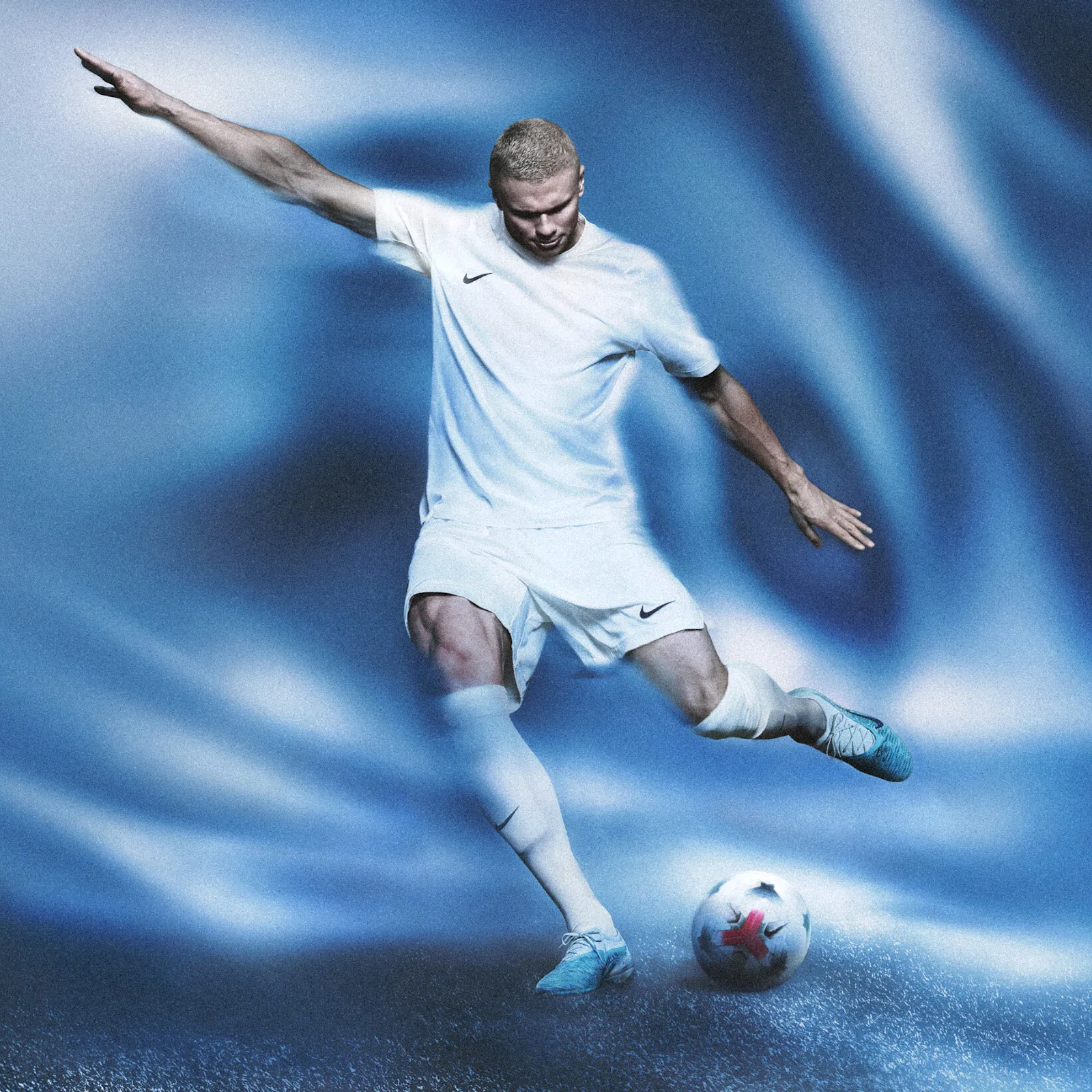 on-foot action shot, player in white kit kicking ball, blue cleats visible, Baltic Blue