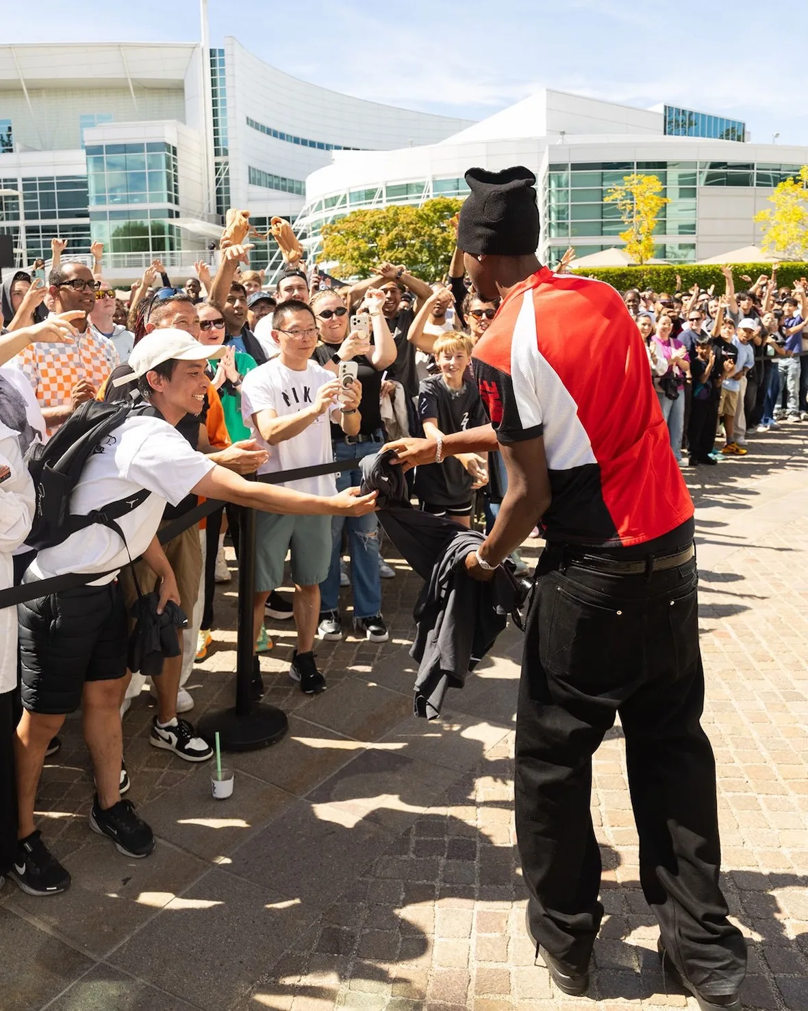 Rear view signing shirts for a crowd, orange and black jersey, black shoes visible, Nike SHAI 002