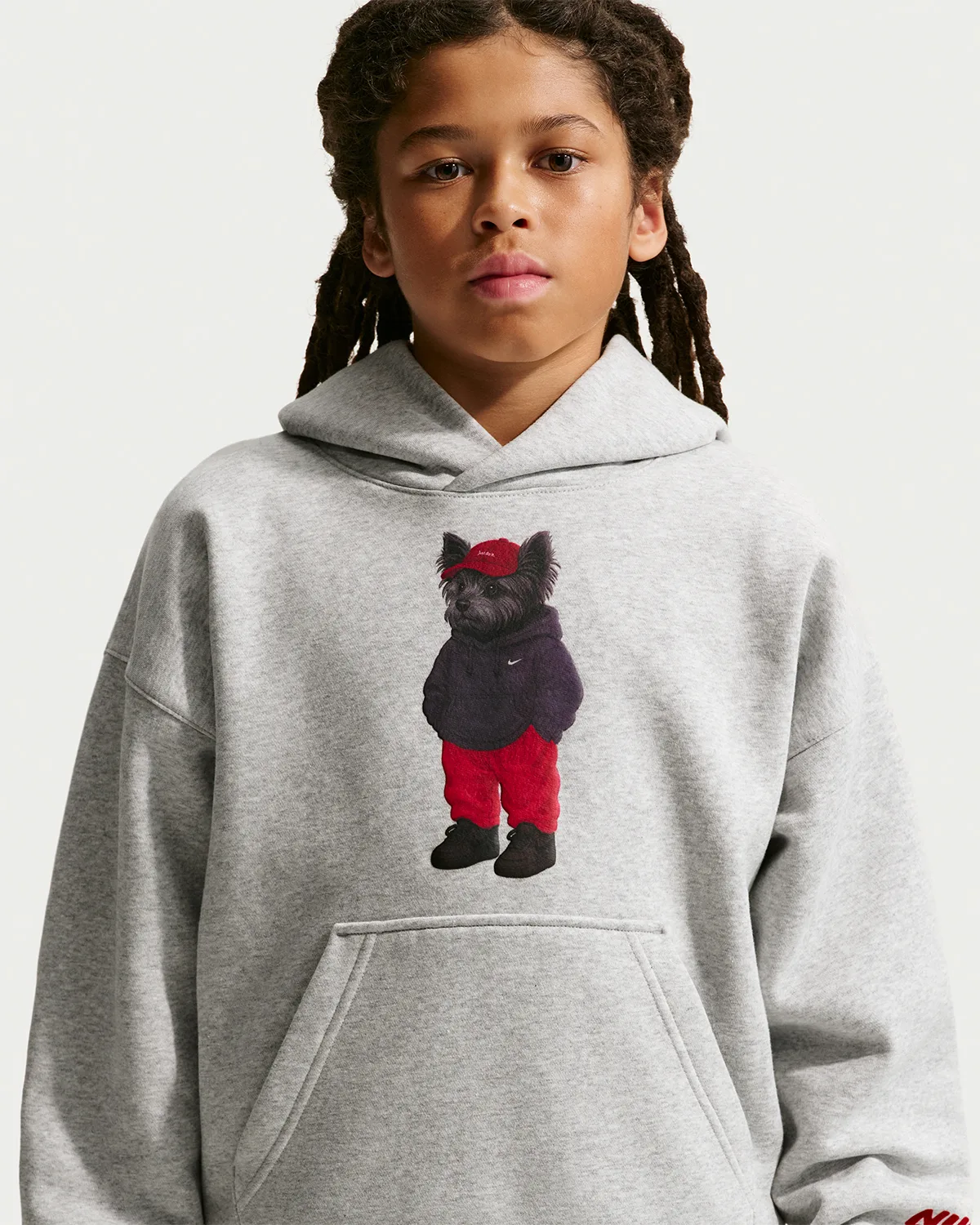 close-up chest detail, grey hoodie with black dog in red pants and cap graphic, Shoe Dog