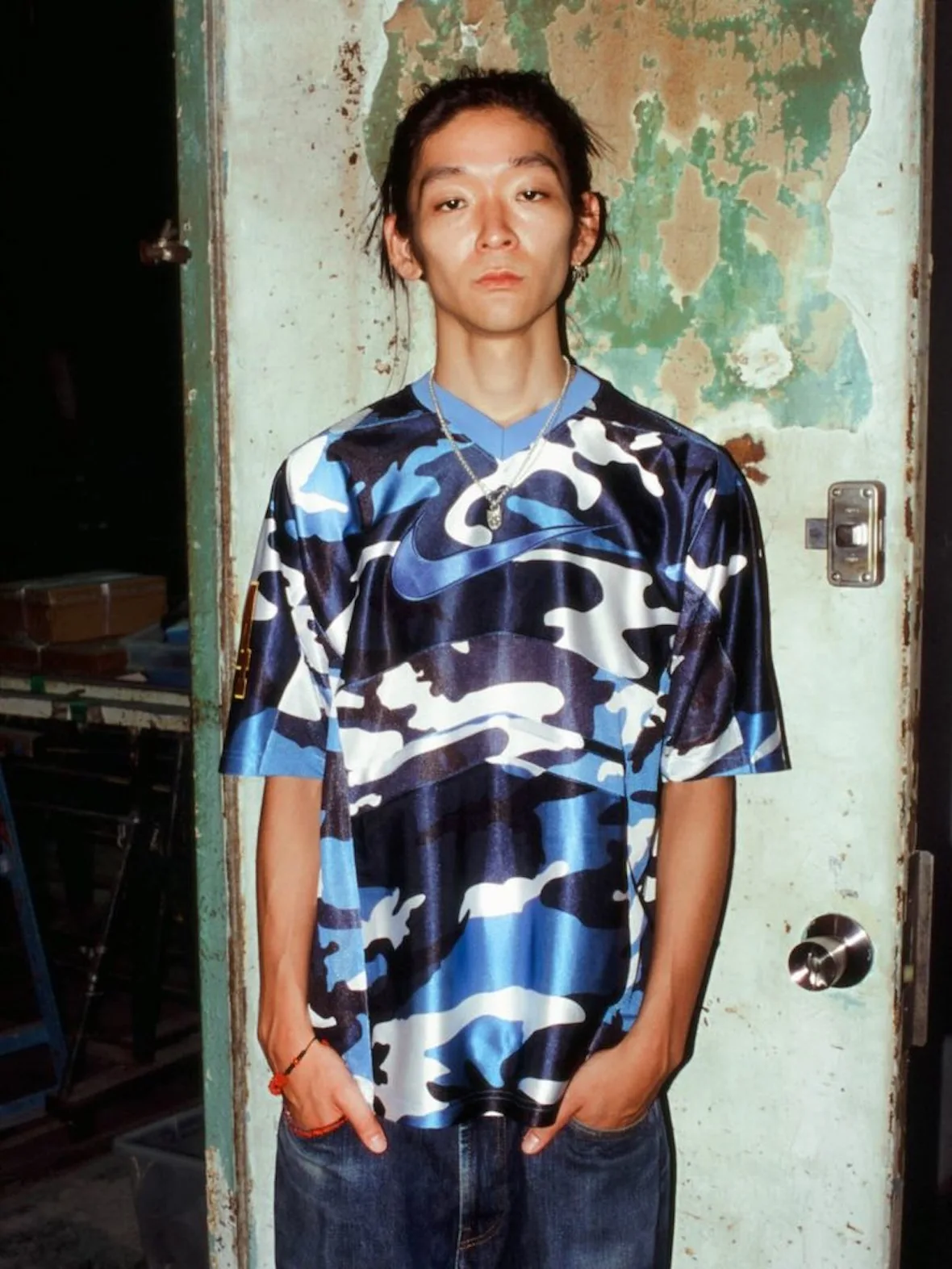 front view, blue camo jersey with large Nike swoosh graphic, worn door background, Fall 2026 Collection