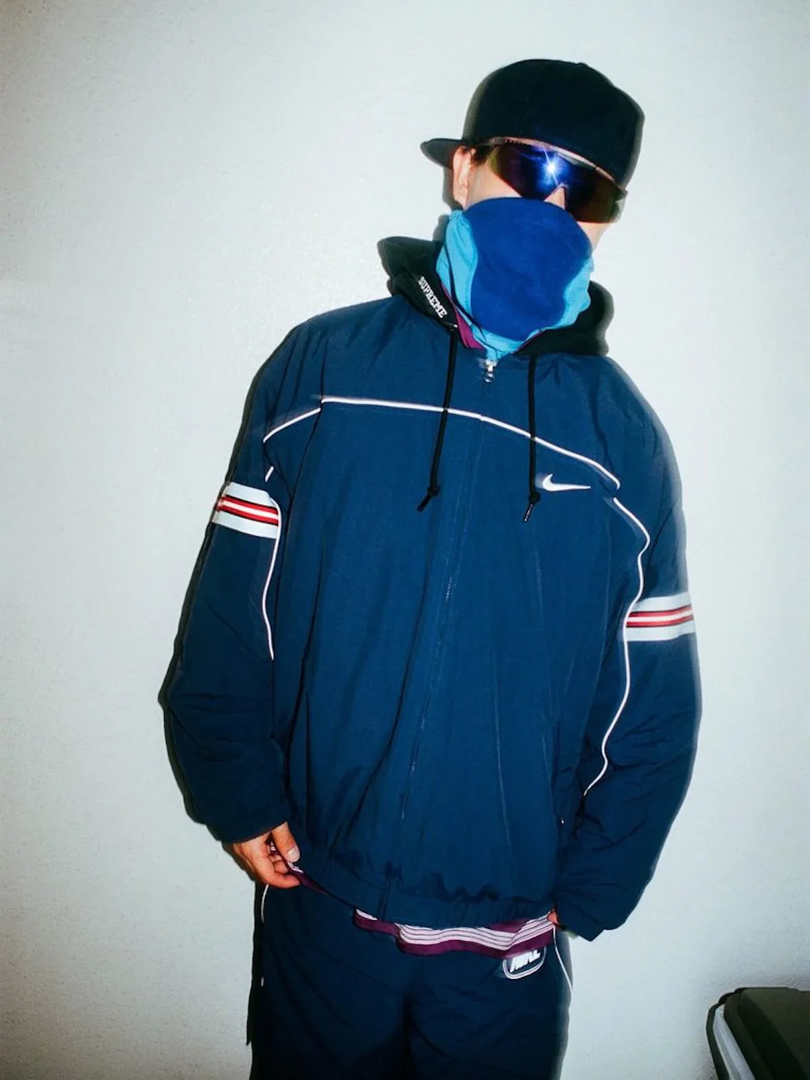 front view, navy jacket with red-striped sleeves, Nike swoosh, blue bandana mask, Fall 2026 Collection
