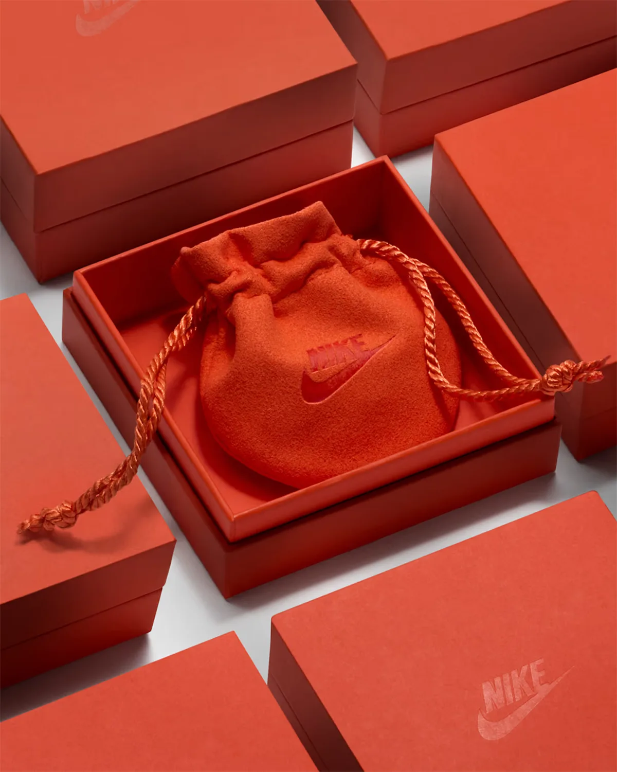 orange suede drawstring pouch with embossed nike logo, nested in orange gift boxes, Swoosh Jewelry Collection