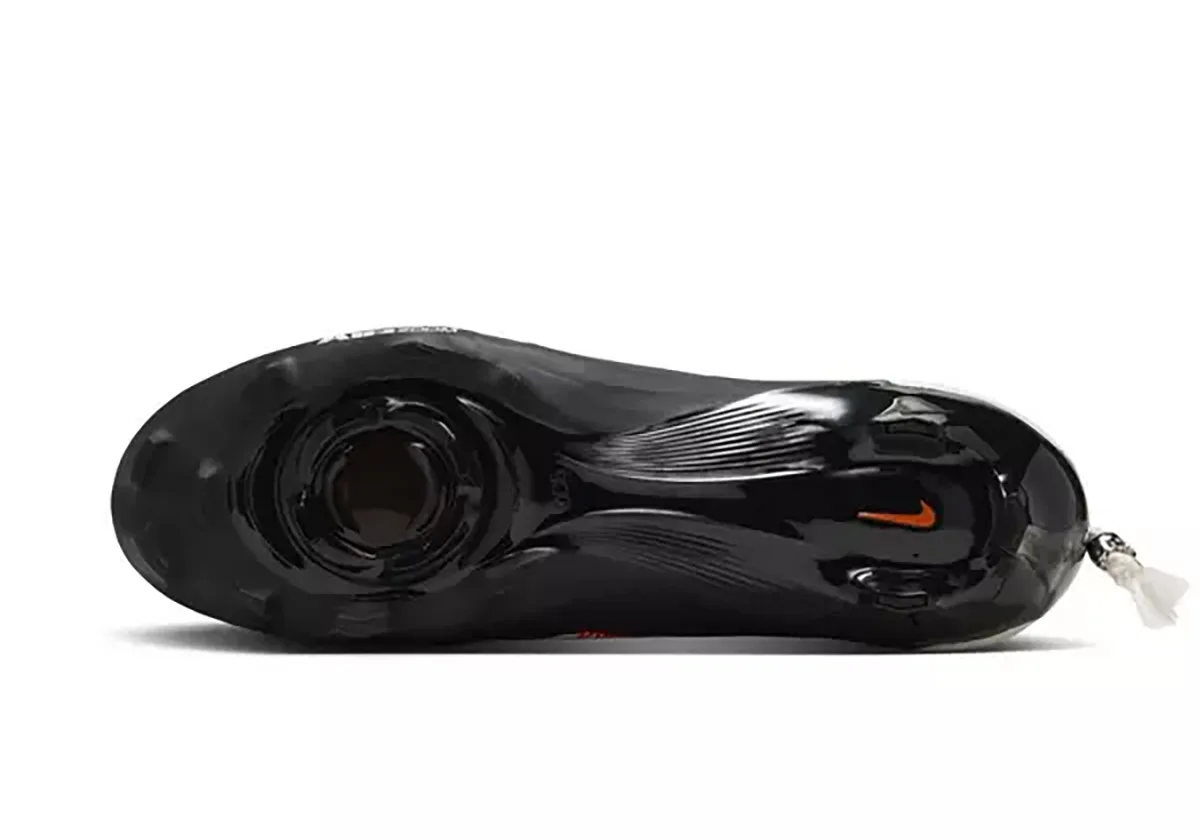 outsole view, black sole with stud pattern and small orange swoosh detail, Skeleton