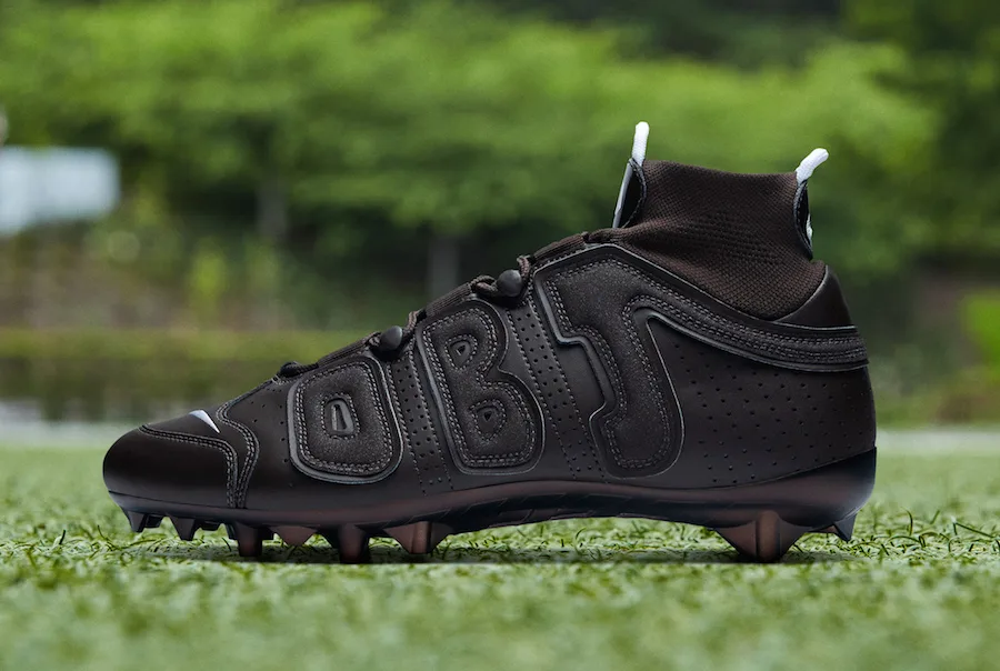 lateral view, all-black tonal upper with 'OBJ' lettering, white lace tips, OBJ Uptempo Cleat